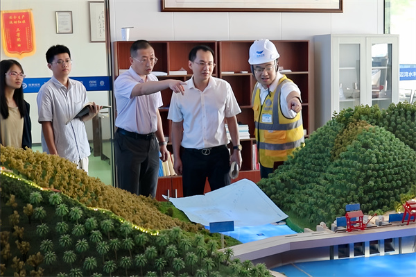 卓豪(右2)在邁灣水利工程審計中查看沙盤
